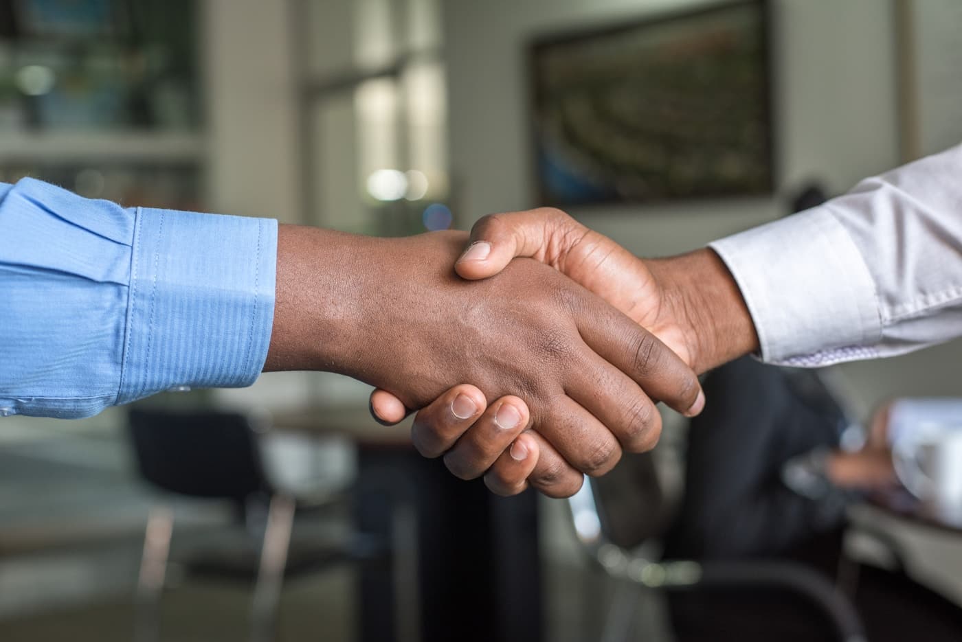 Two people shaking hands across a table in a professional meeting