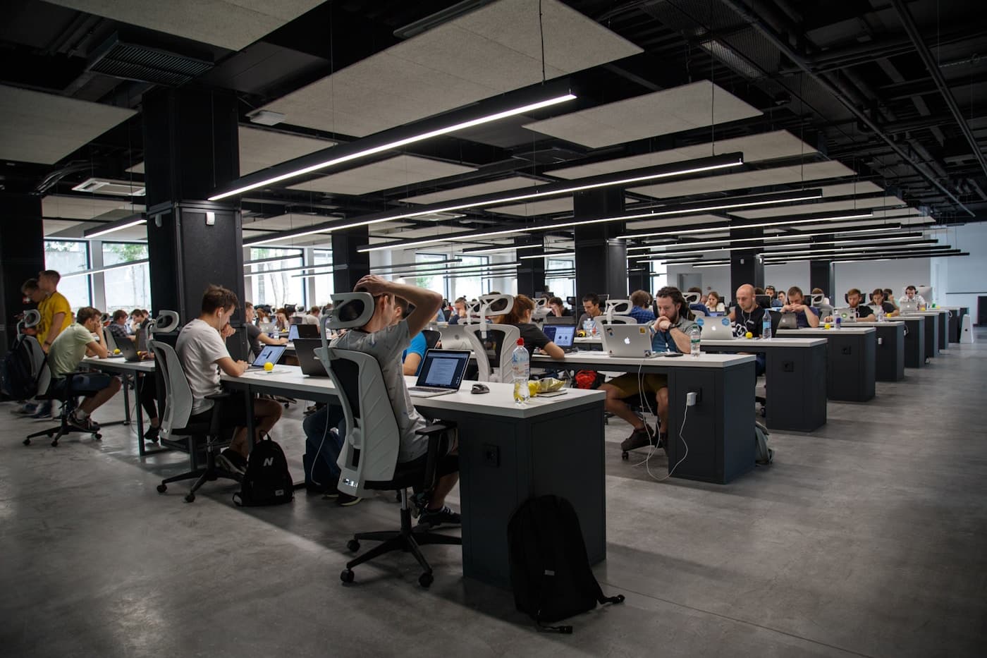 Person working at a laptop in a bright open office with large windows