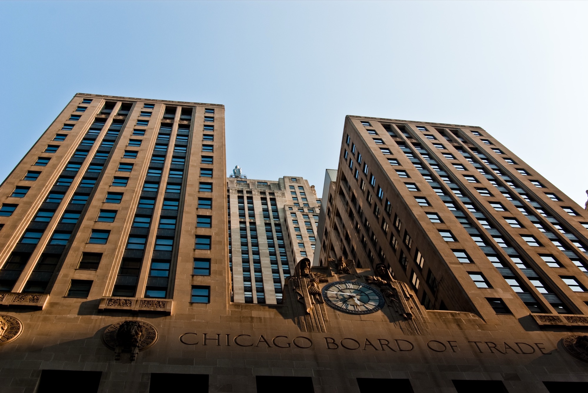 Chicago Board of Trade Building facade with Art Deco tower and sculpture against a blue sky
