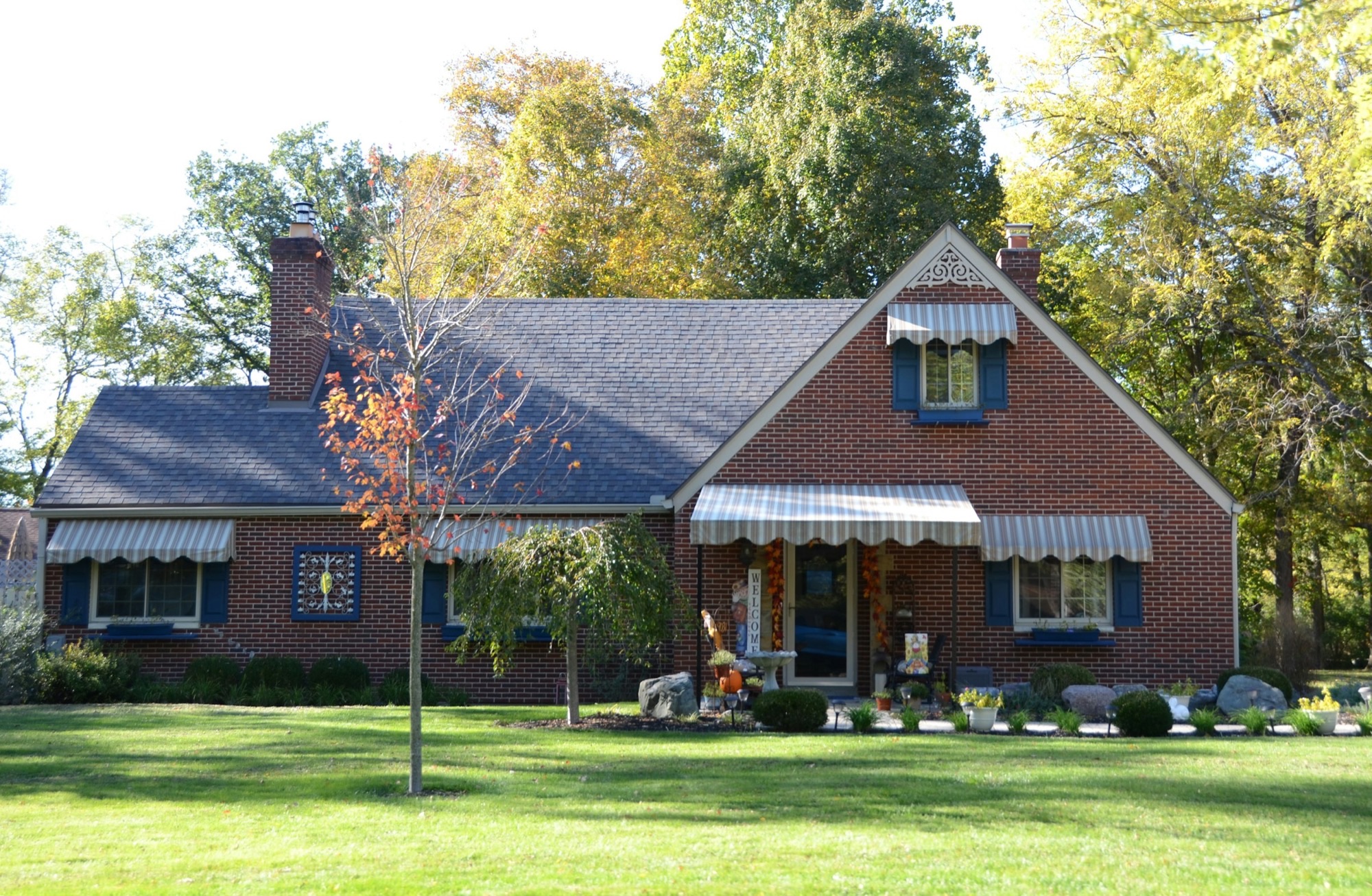 Red brick suburban house with a green front lawn and trees