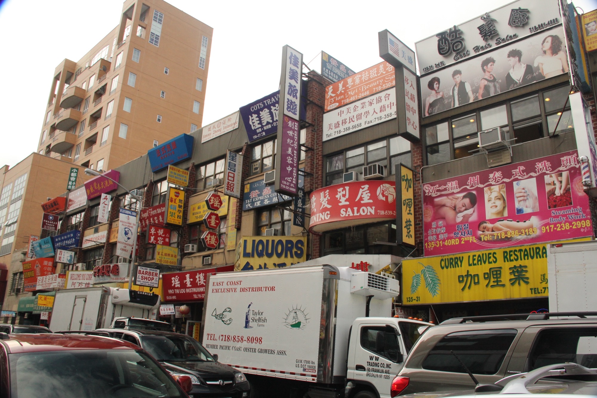Dense bilingual shop signs along a commercial street in Flushing, Queens