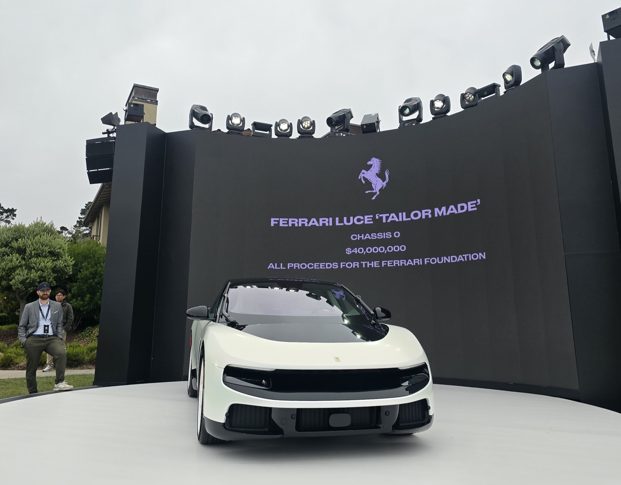 Ferrari Luce Chassis 0 on a white turntable at Monterey Car Week, with a screen behind it reading Chassis 0 and $40,000,000 for the Ferrari Foundation