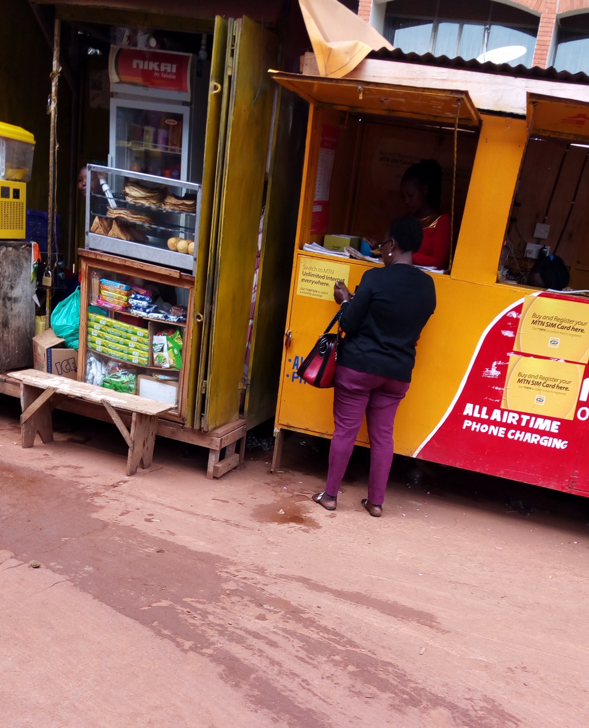 A woman makes a transaction at a mobile money kiosk in Uganda