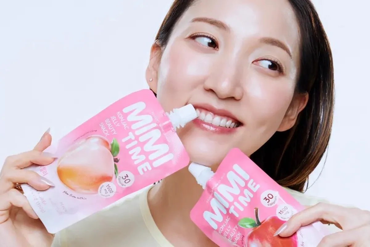 Ava Lee holding peach and apple Mimitime konjac jelly beauty snack pouches against a white background