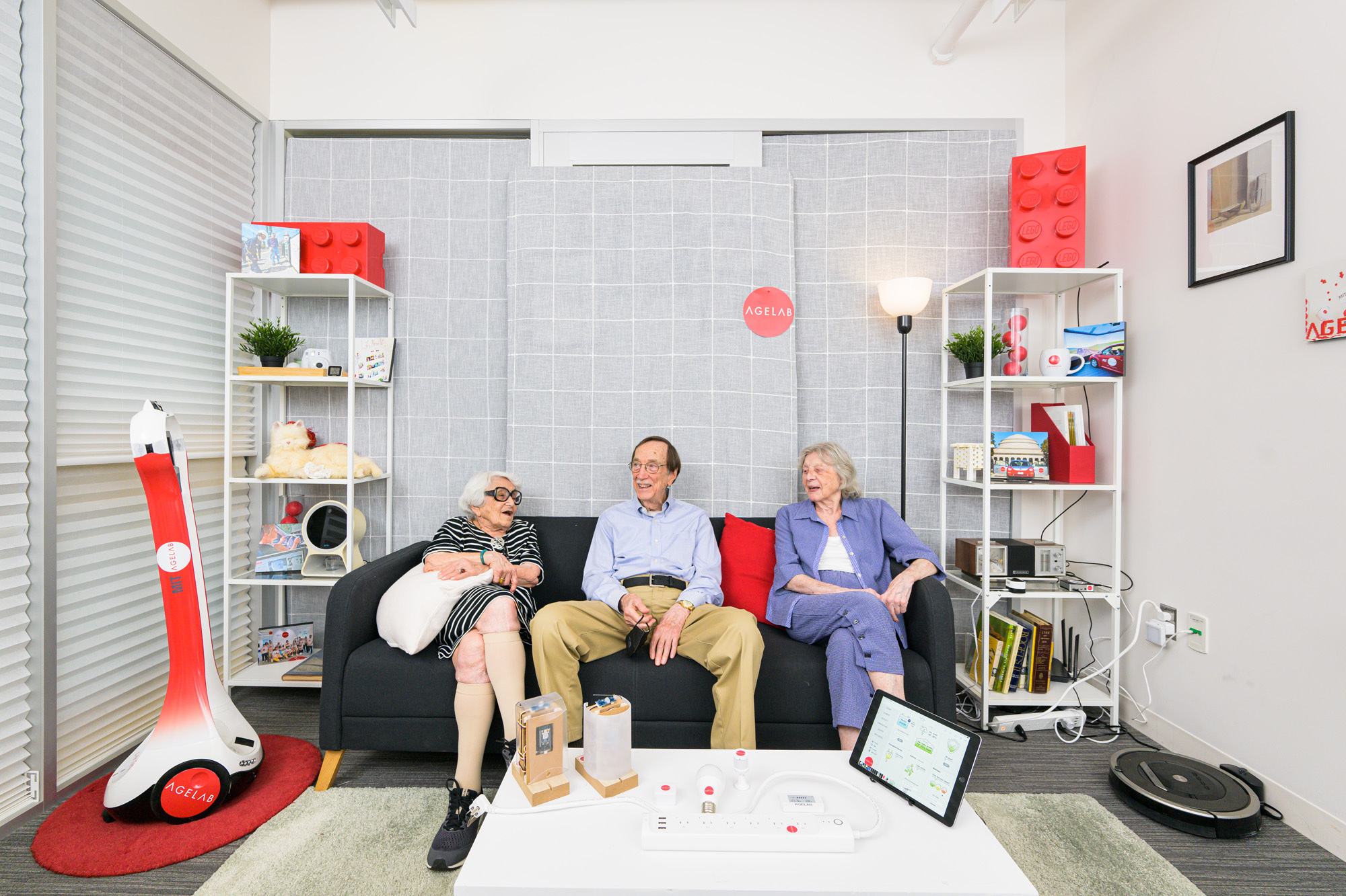 Older adults in MIT AgeLab’s living-room research space with smart-home tech and an AgeLab robot