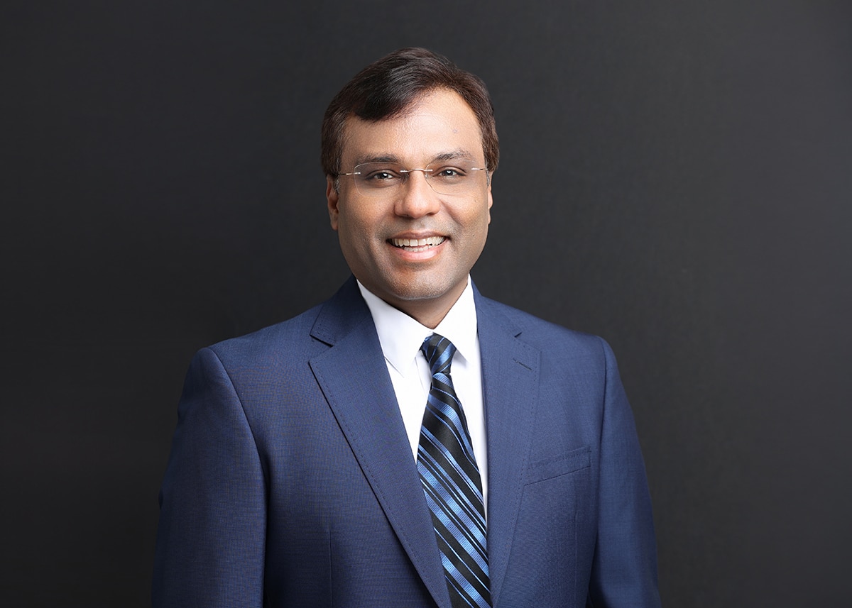 Portrait of Rohit Prasad in a blue suit against a dark background