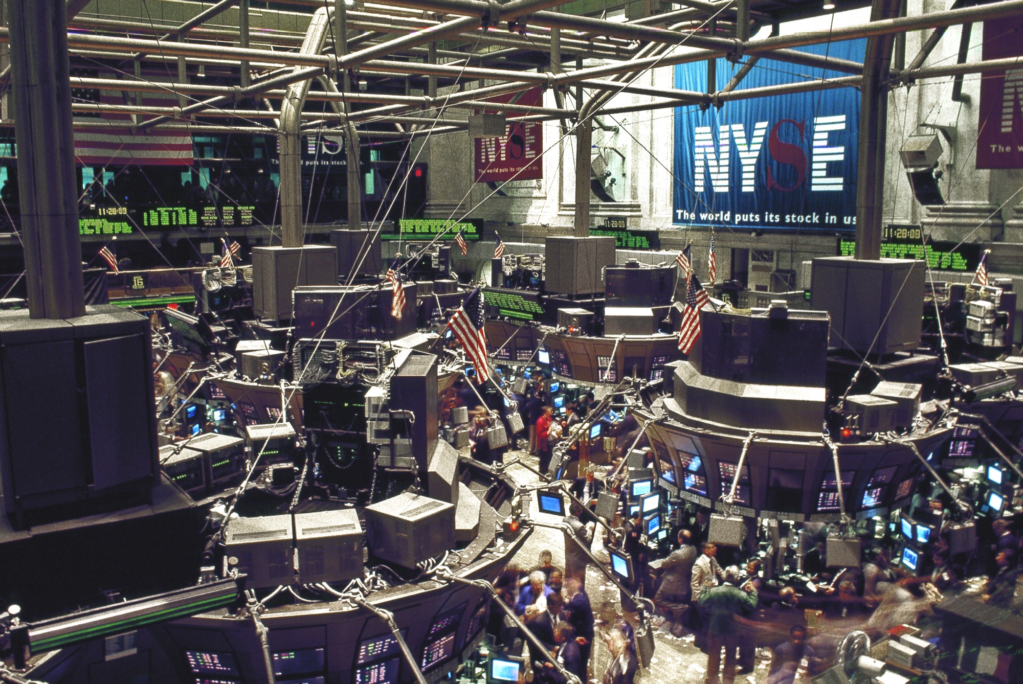 Traders and screens on the New York Stock Exchange floor under the NYSE banner