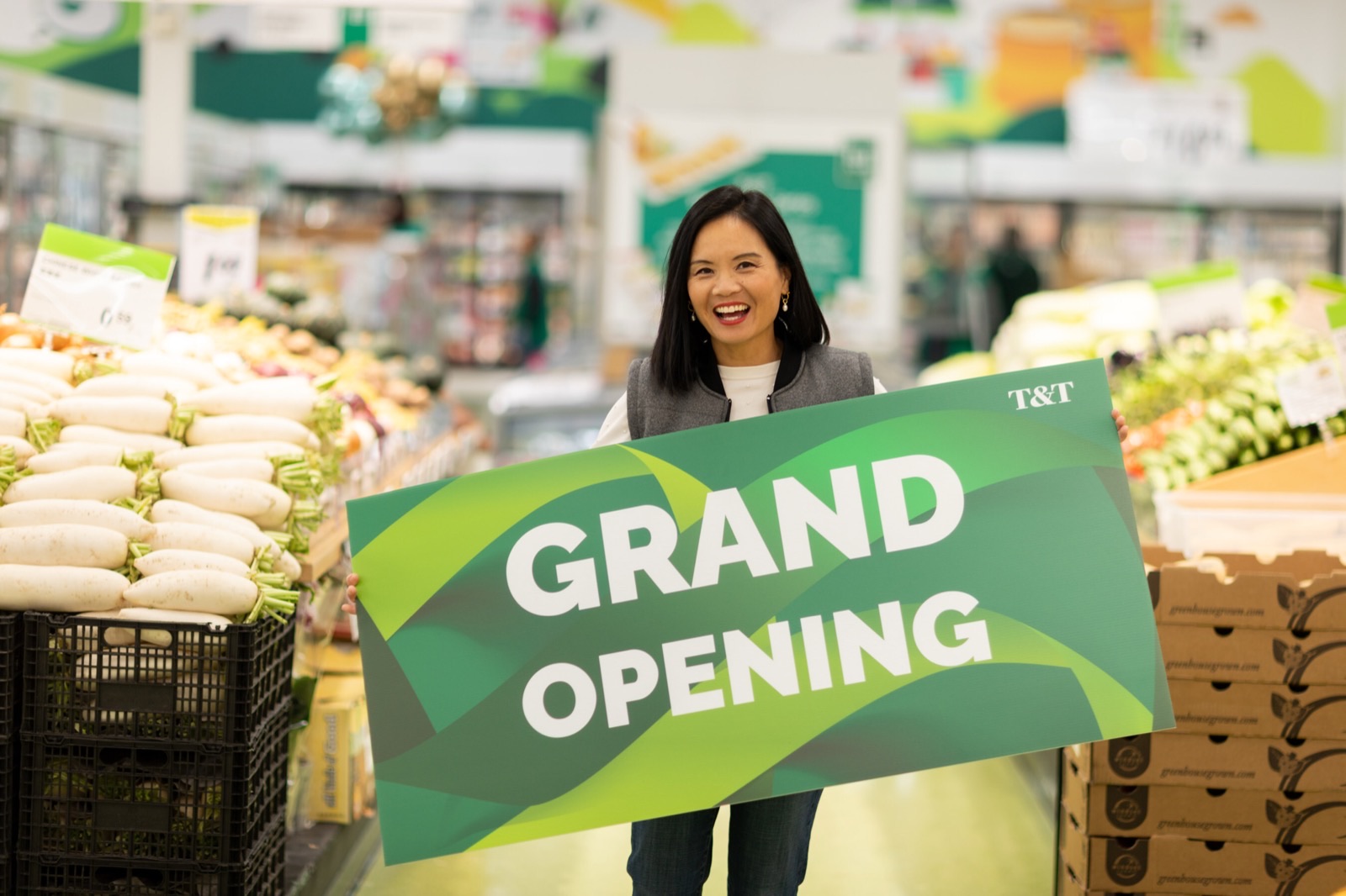 Tina Lee, CEO of T&T Supermarket, holds a grand-opening sign in a produce aisle