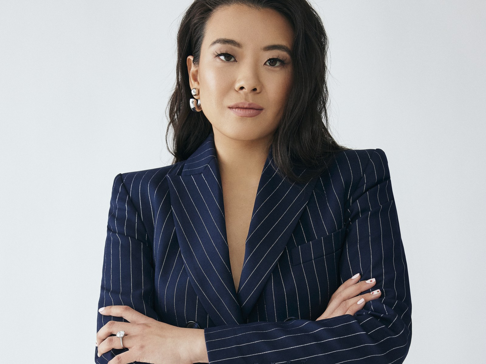 Portrait of Vivian Tu, founder of Your Rich BFF, in a navy pinstripe blazer with arms crossed